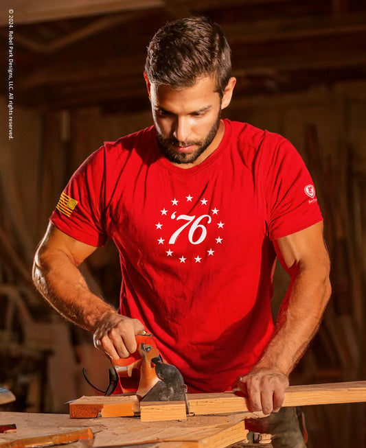 Man in a red shirt with a logo working with tools in a workshop.