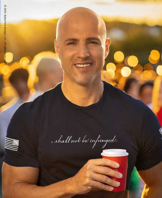 Man wearing a black t-shirt with text, holding a red cup in a blurred outdoor setting