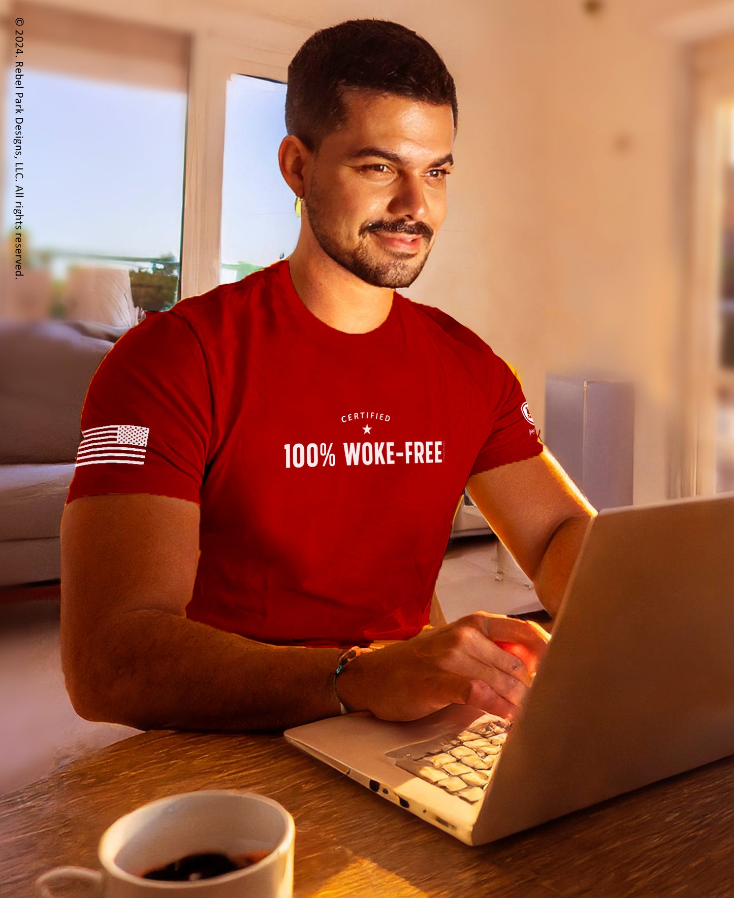 Man wearing a red t-shirt with text, using a laptop in a home setting