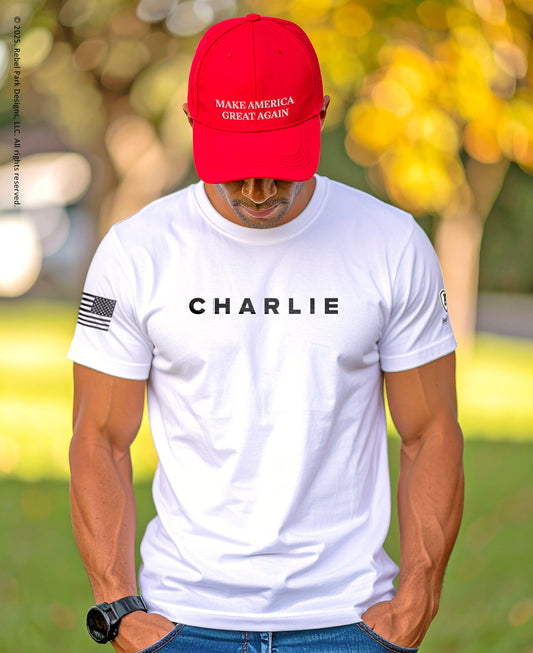 Person wearing a white t-shirt with 'CHARLIE' printed on it, a red cap with 'MAKE AMERICA GREAT AGAIN', and an American flag patch.