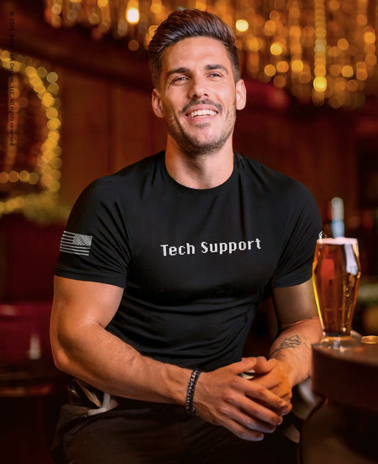 Man wearing a black 'Tech Support' t-shirt in a bar setting