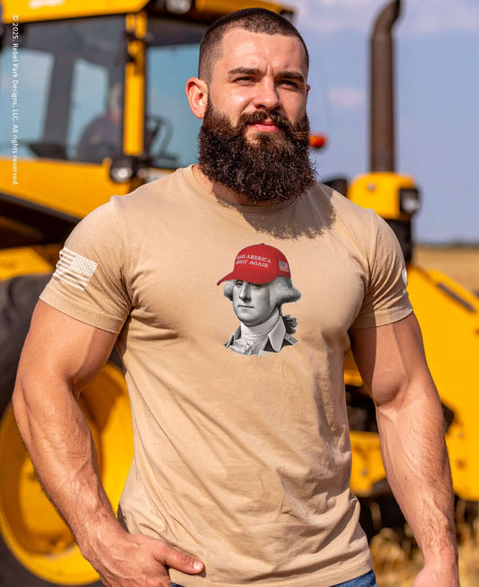 Man wearing a beige t-shirt with a graphic design in front of a yellow construction vehicle.