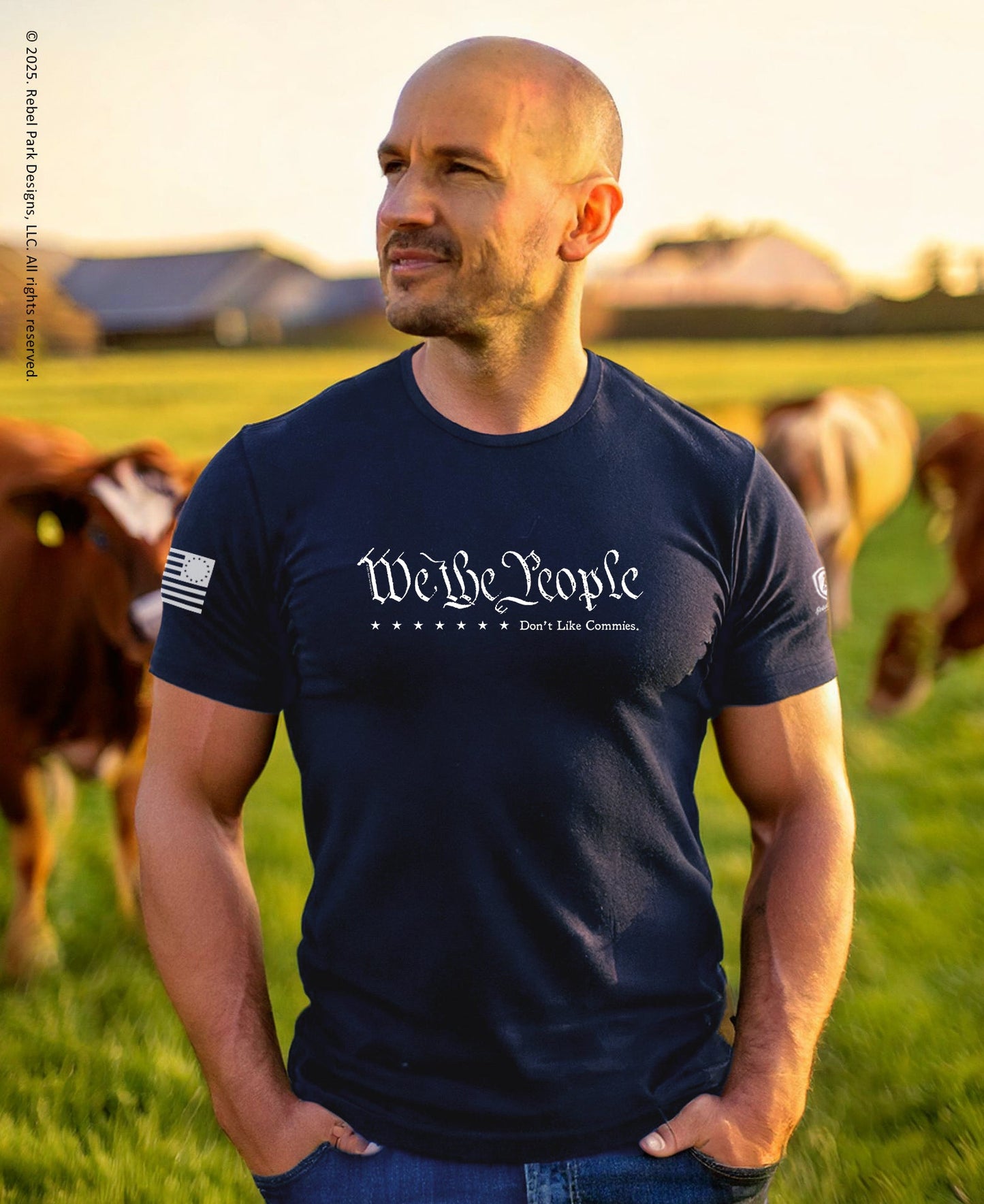 Man wearing a navy blue t-shirt with 'We the People' text in a field with cows.