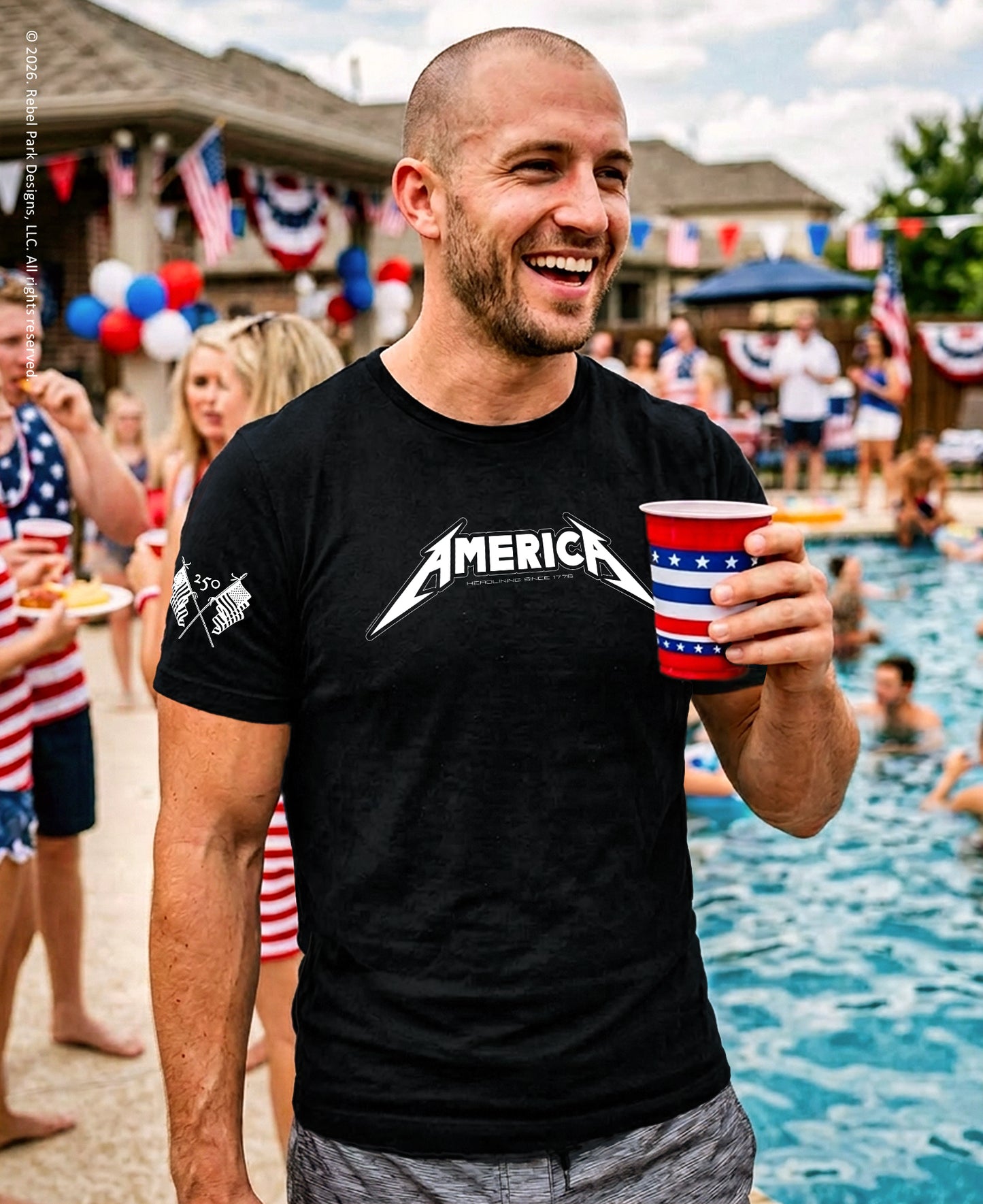 Man wearing a black t-shirt with 'AMERICA' printed on it, holding a red and white cup, standing by a pool with people around.