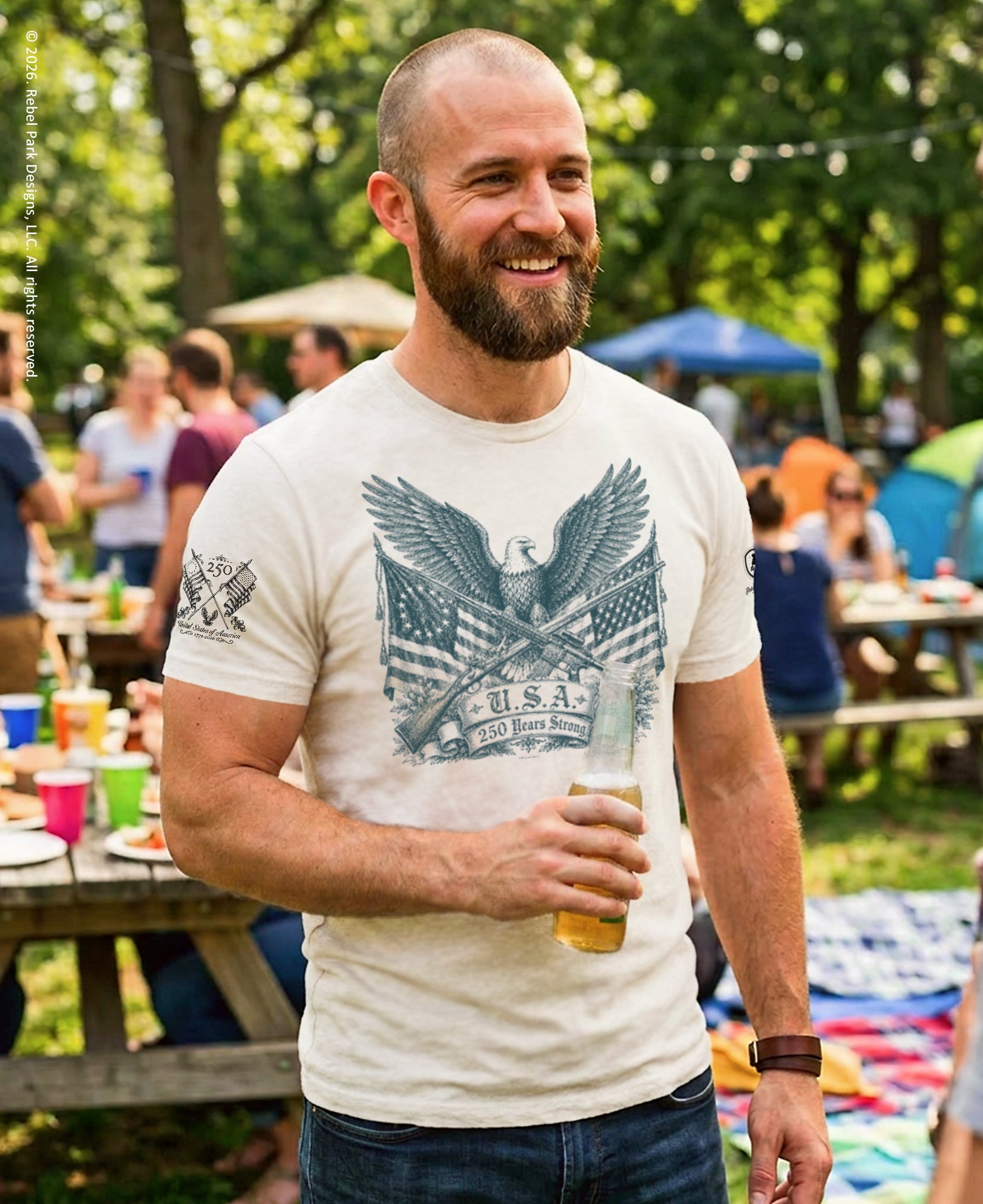 Man holding a beer at an outdoor gathering with people and tents in the background