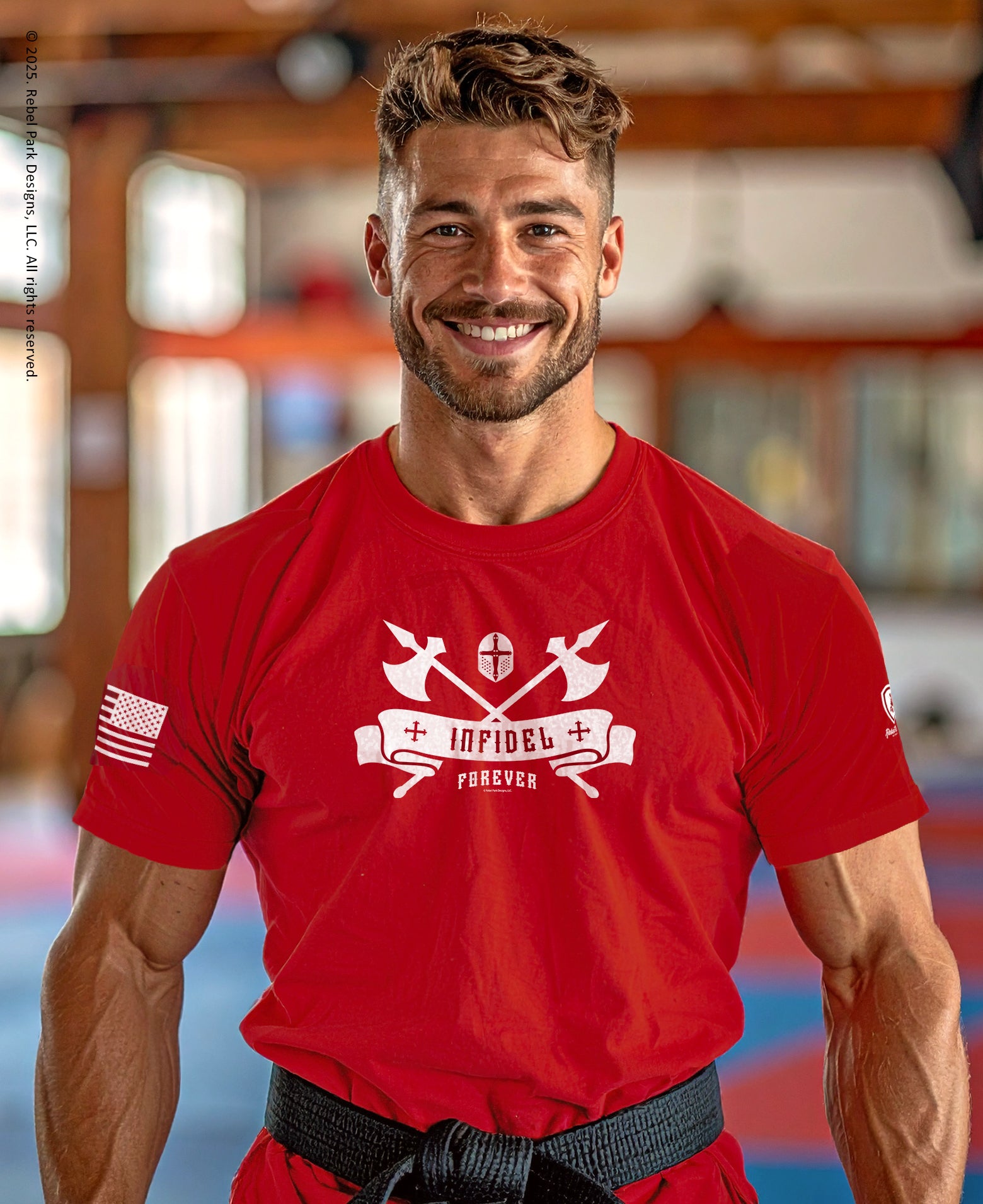 Man wearing a red t-shirt with a logo and text, standing indoors.