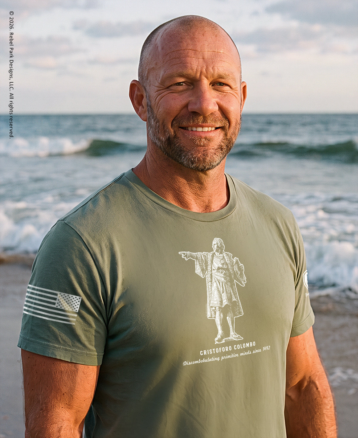 Man standing on a beach wearing a sage t-shirts