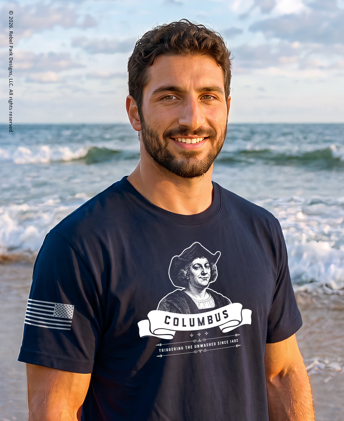 Man standing on a beach wearing a columbus t-shirt