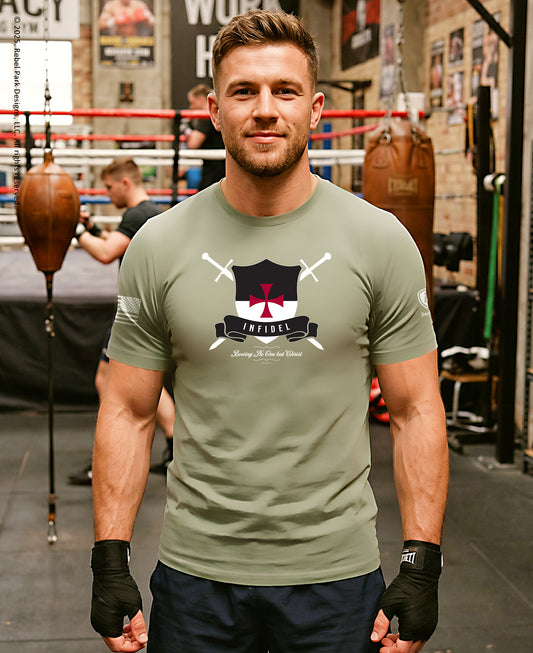 A man in a boxing gym wearing an olive green t-shirt with a black and red shield graphic that reads 'ARMAGEDDON'.