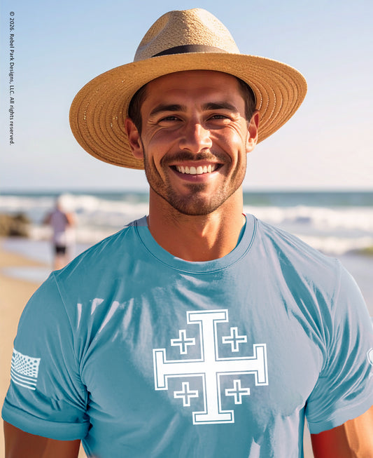 Man wearing a straw hat and blue t-shirt with a white logo on a beach.