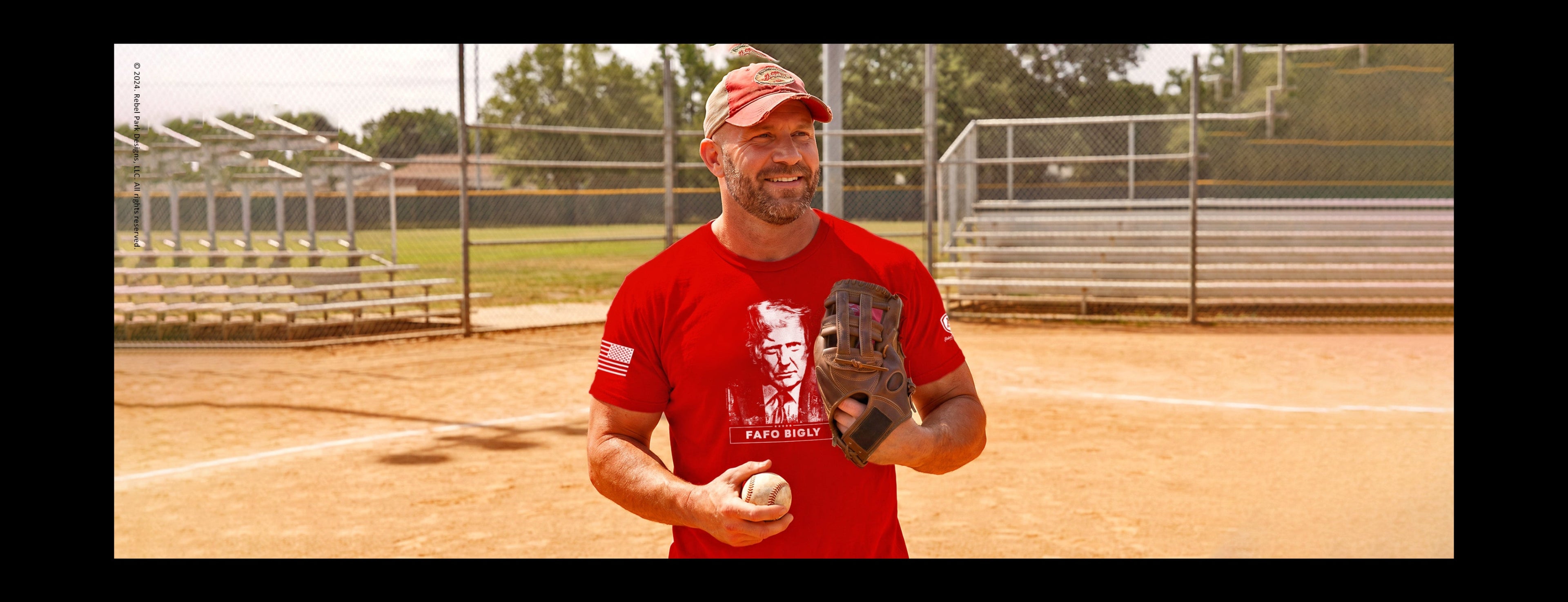 Man in red shirt and cap holding a baseball glove and ball on a baseball field