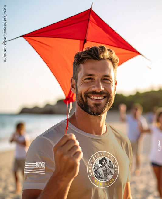 Man holding a red kite on a beach with people in the background