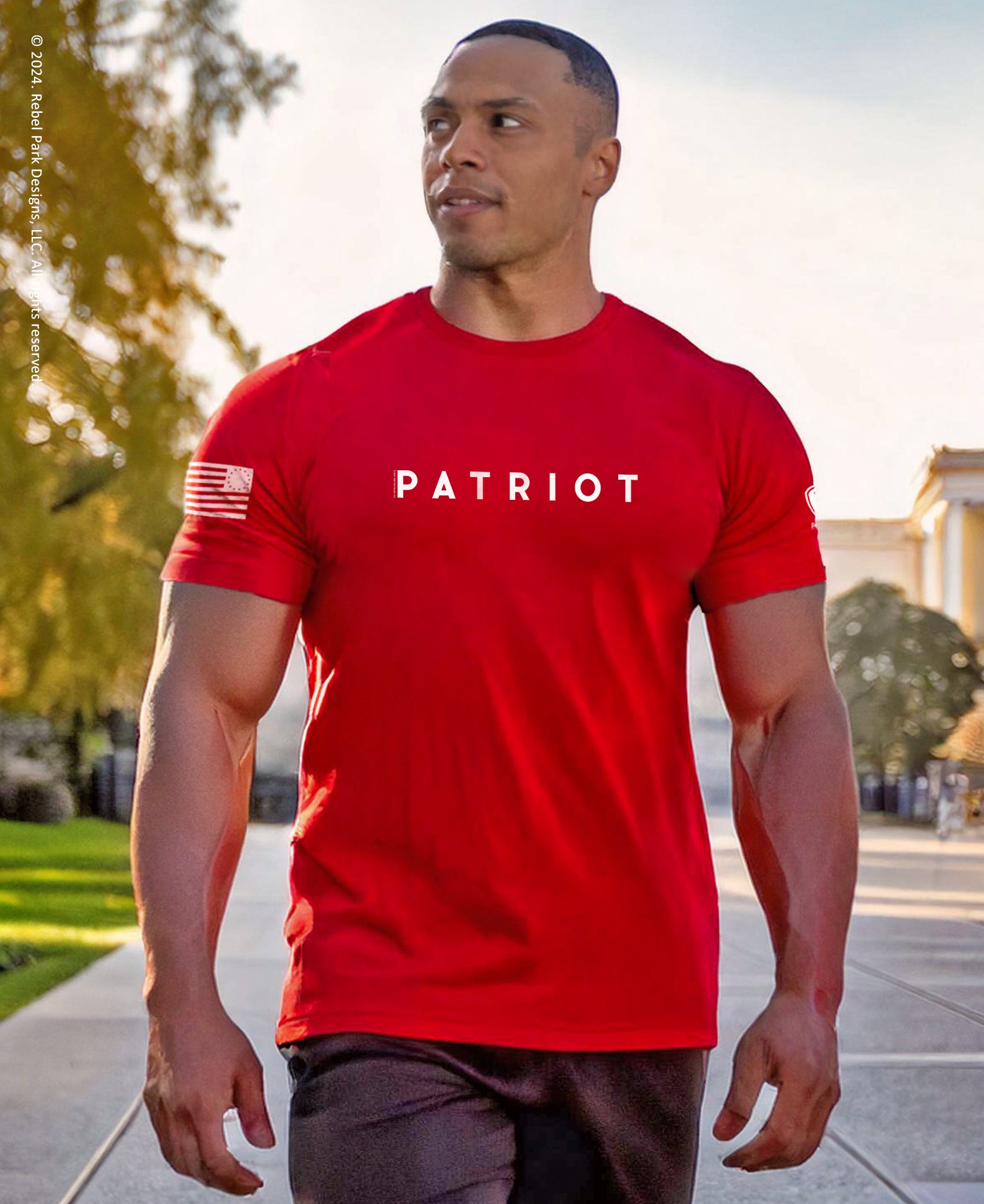 Man wearing a red 'Patriot' t-shirt walking outdoors.