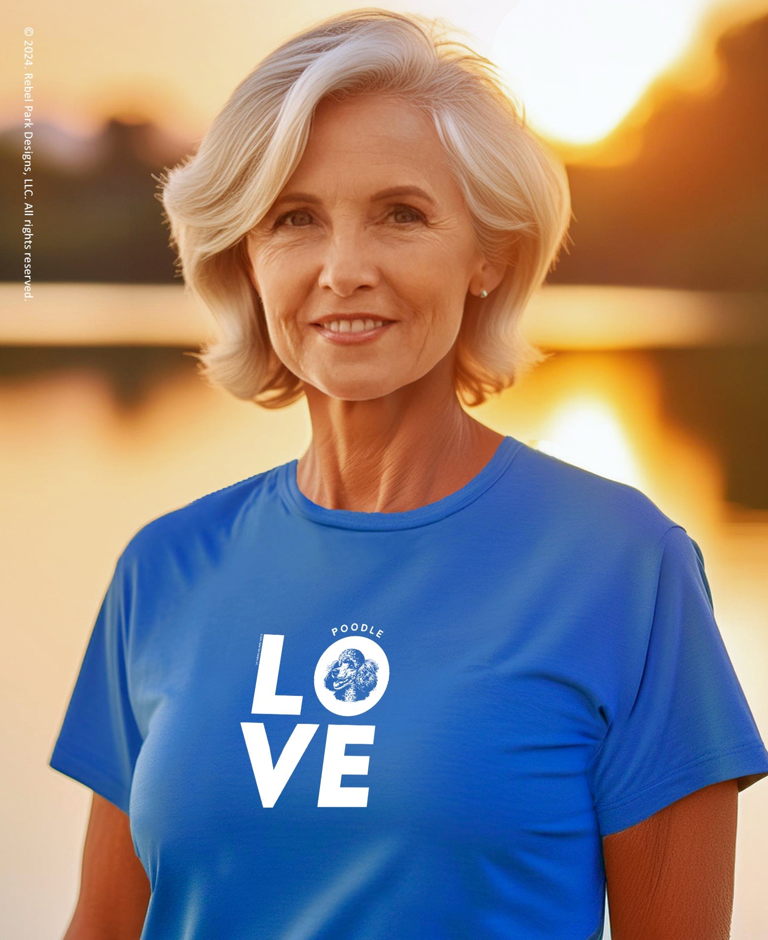 Woman wearing a blue t-shirt with 'POODLE LOVE' printed on it, standing against a sunset background.