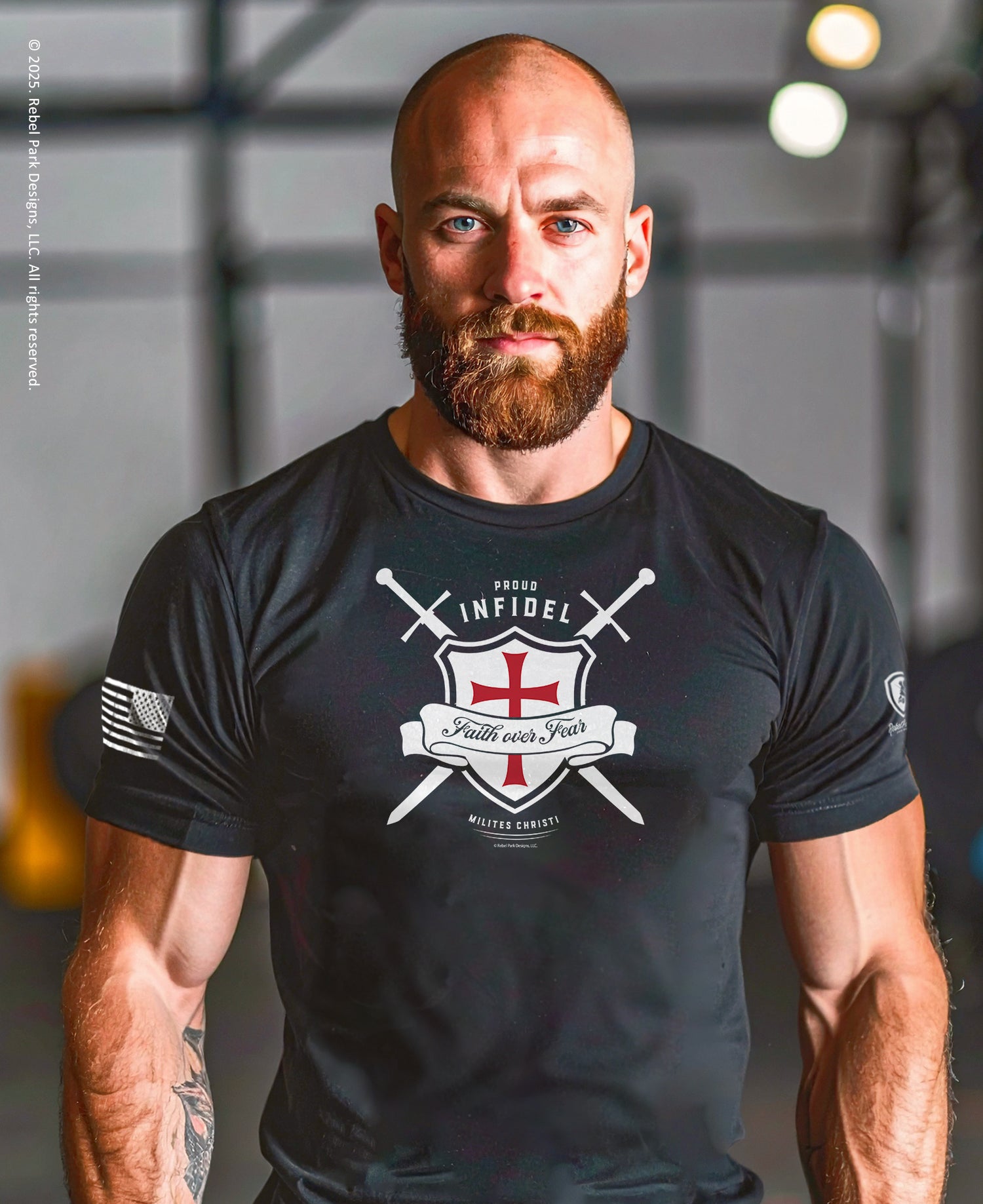 Man wearing a black t-shirt with a logo and text, standing indoors.