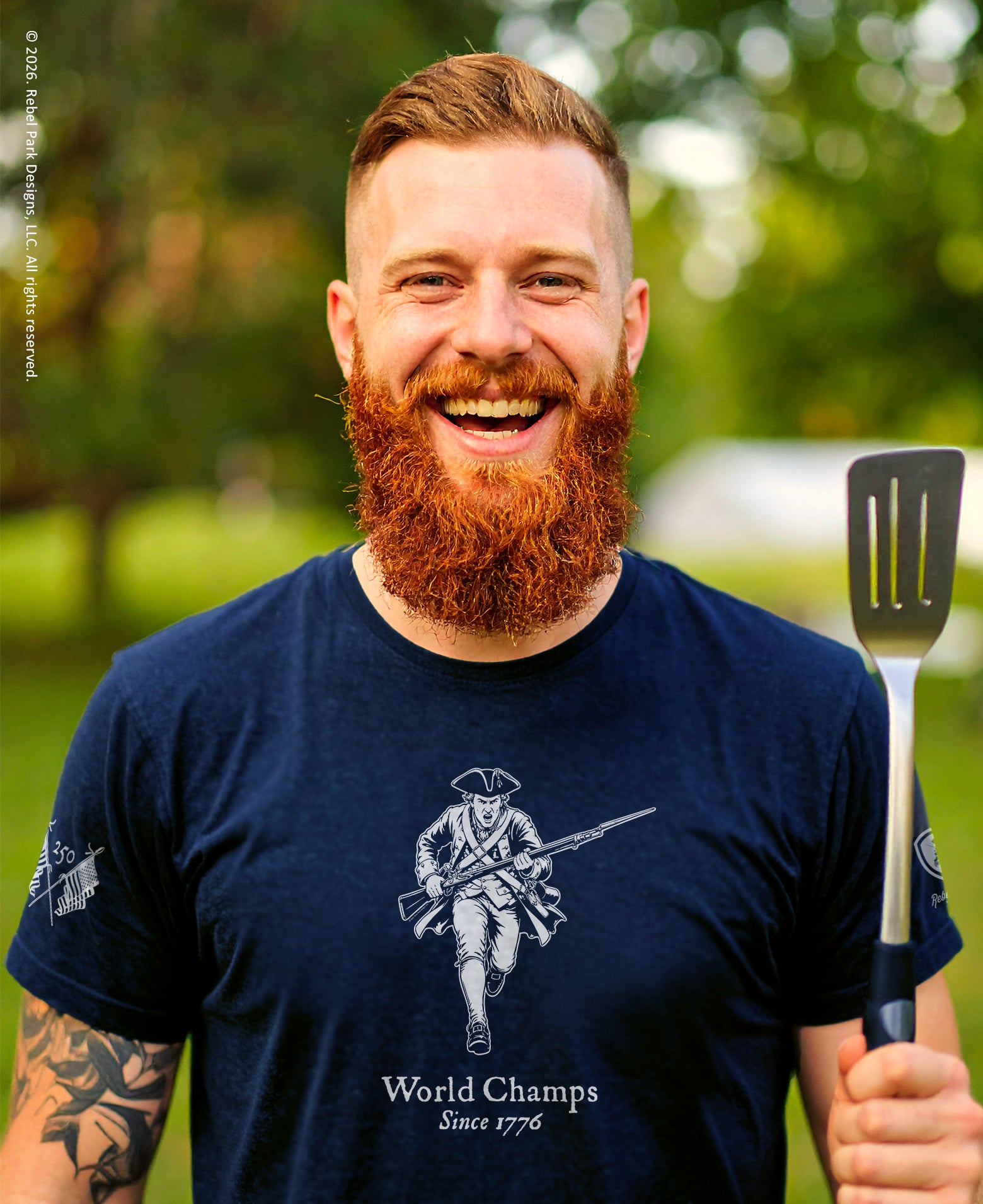 Man with a beard holding a spatula outdoors